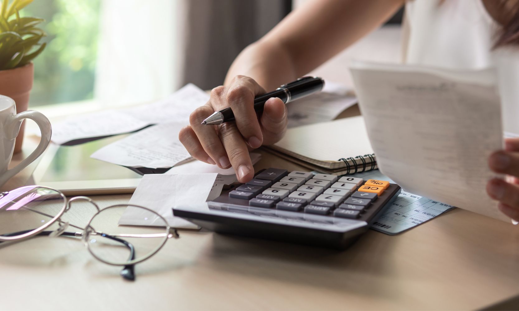 Image of a woman calculating bills at a table