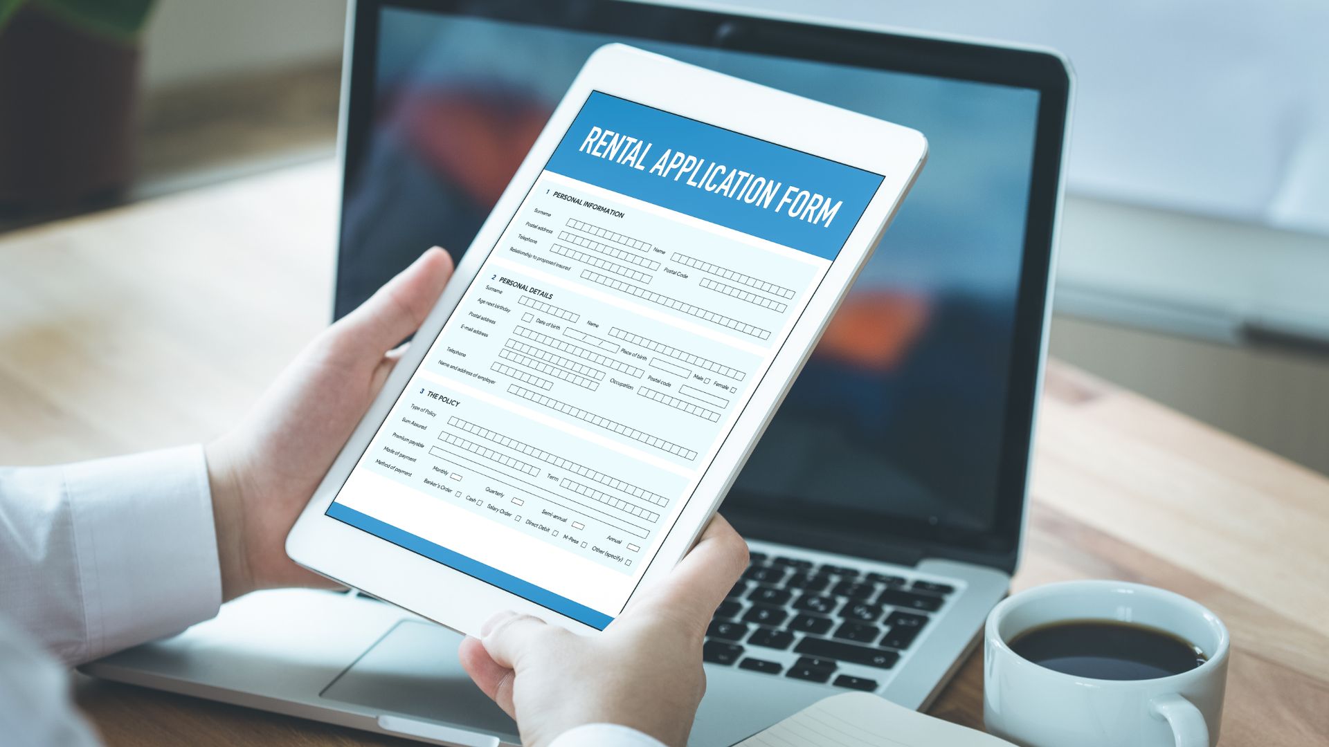 Image of a person holding a tablet with a rental application form on the screen