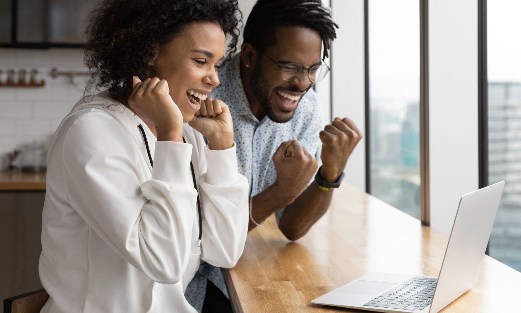 Image of a happy couple who received good news from their computer