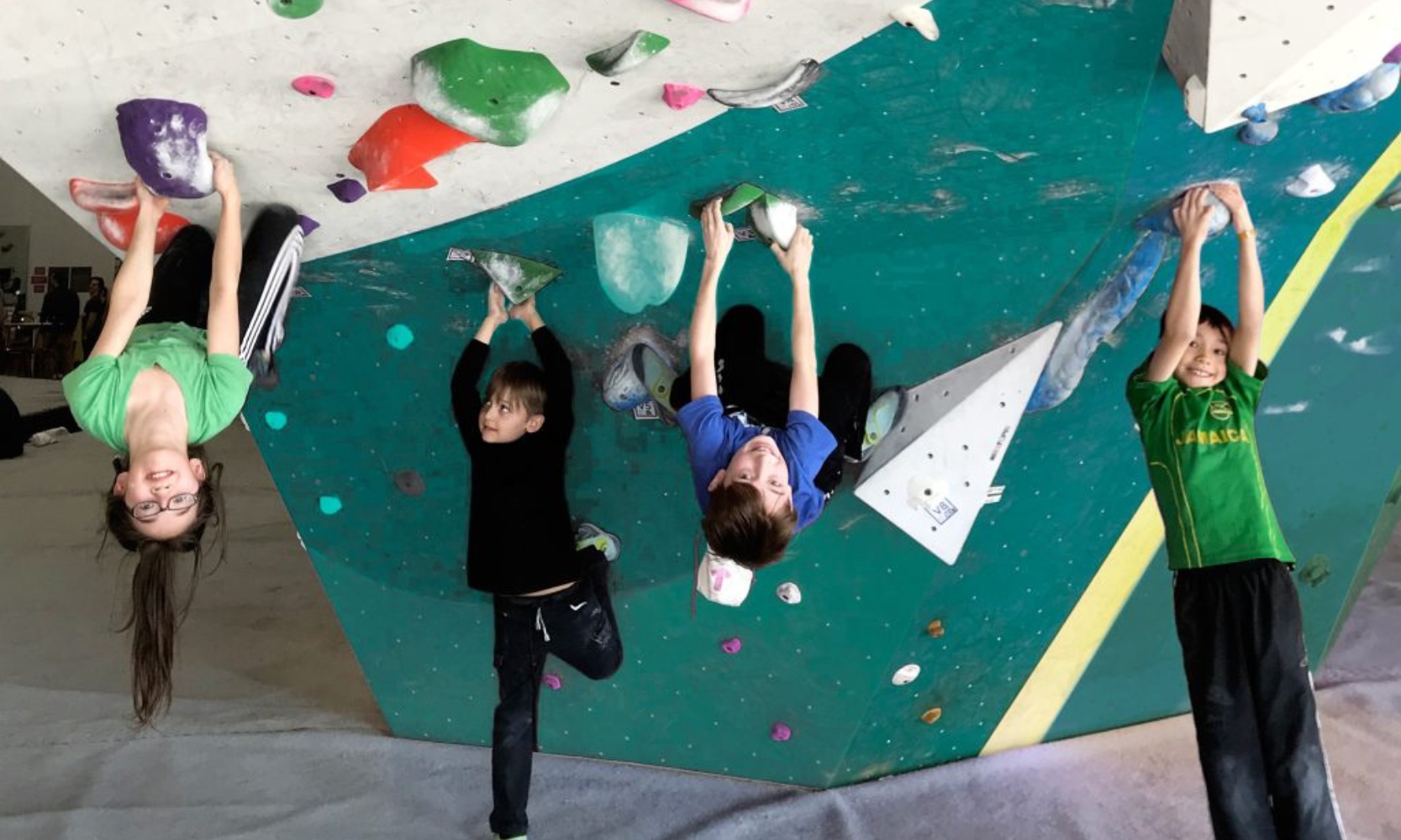 Closeup image of four children climbing a rock wall at the First Ascent gym in Arlington Heights, IL