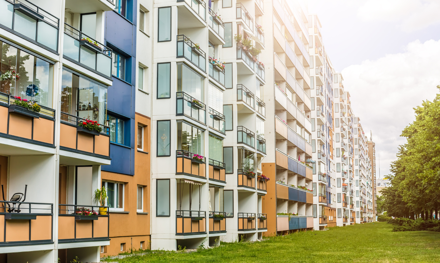 Image of a mid-rise apartment building complex with greenery in front of it
