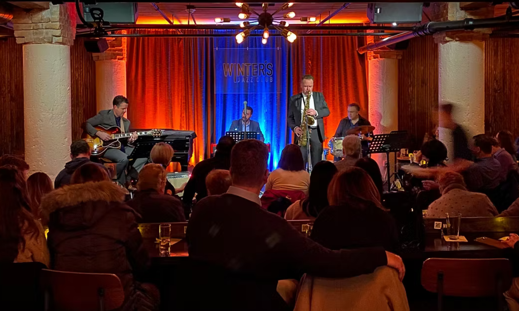 Interior image of the Winter's Jazz Club venue in Chicago with a jazz band performing and people watching