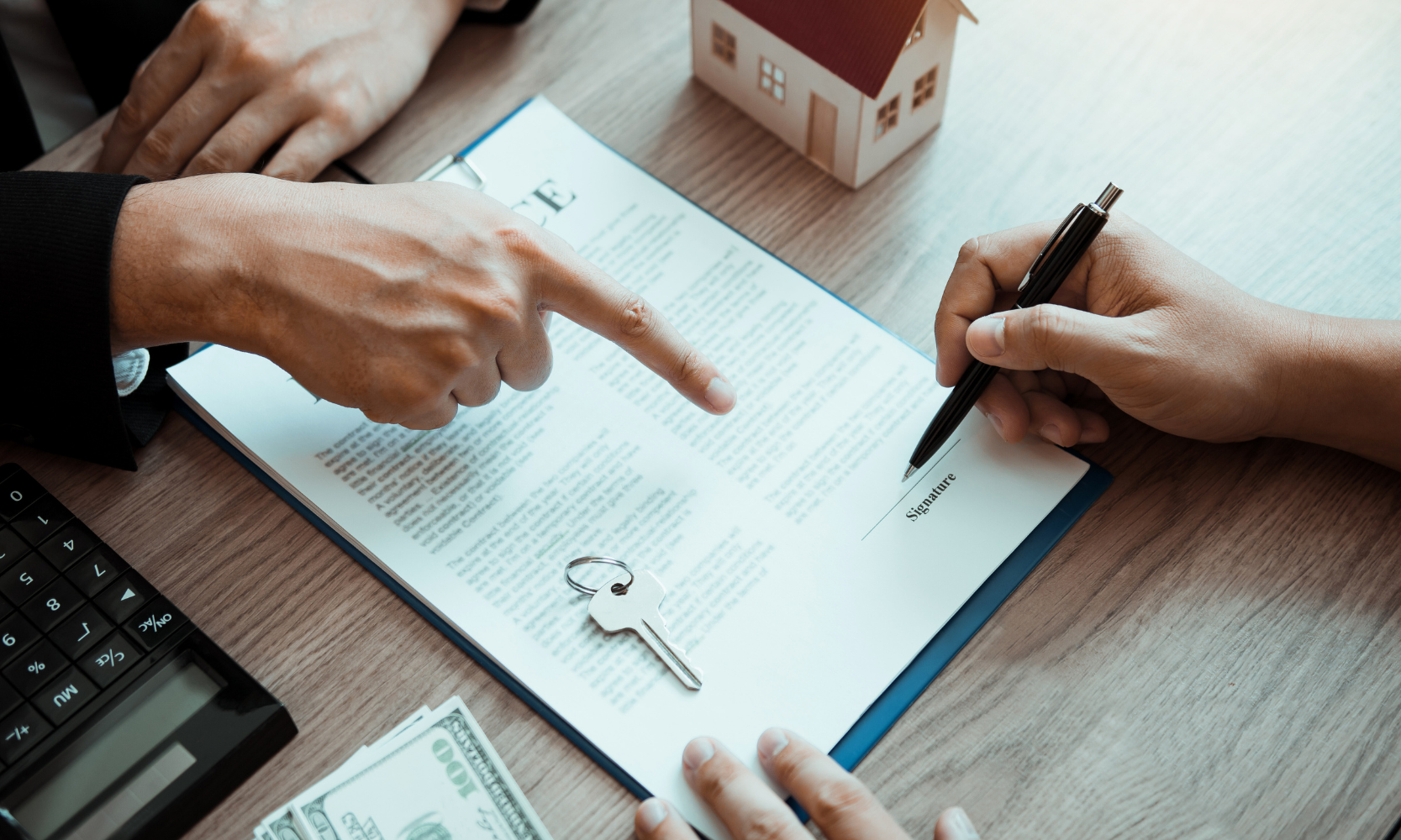 Closeup image of a person signing an insurance document with an agency at a desk